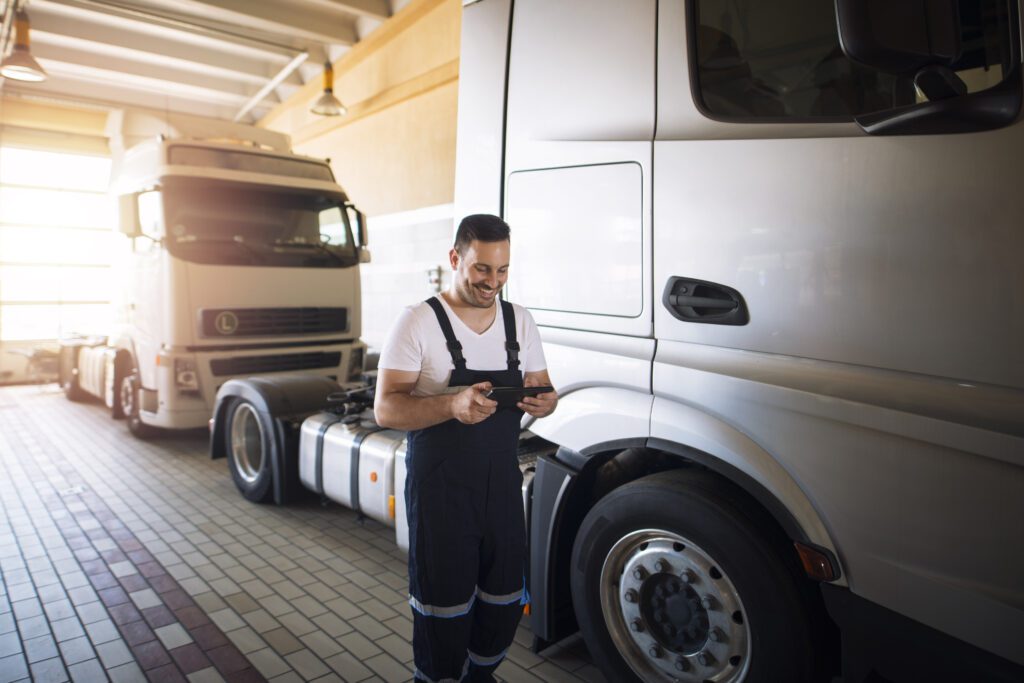Truck maintenance and service workshop. Truck mechanic with tablet diagnostic tool preparing trucks for maintenance.