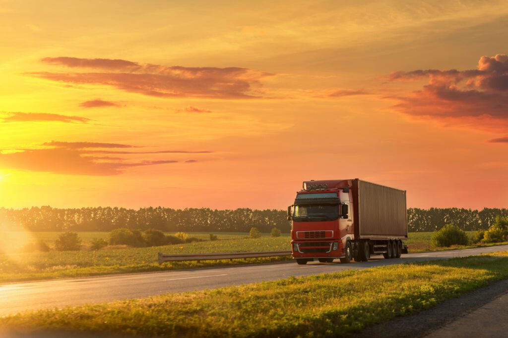 Truck driving on road with sunset