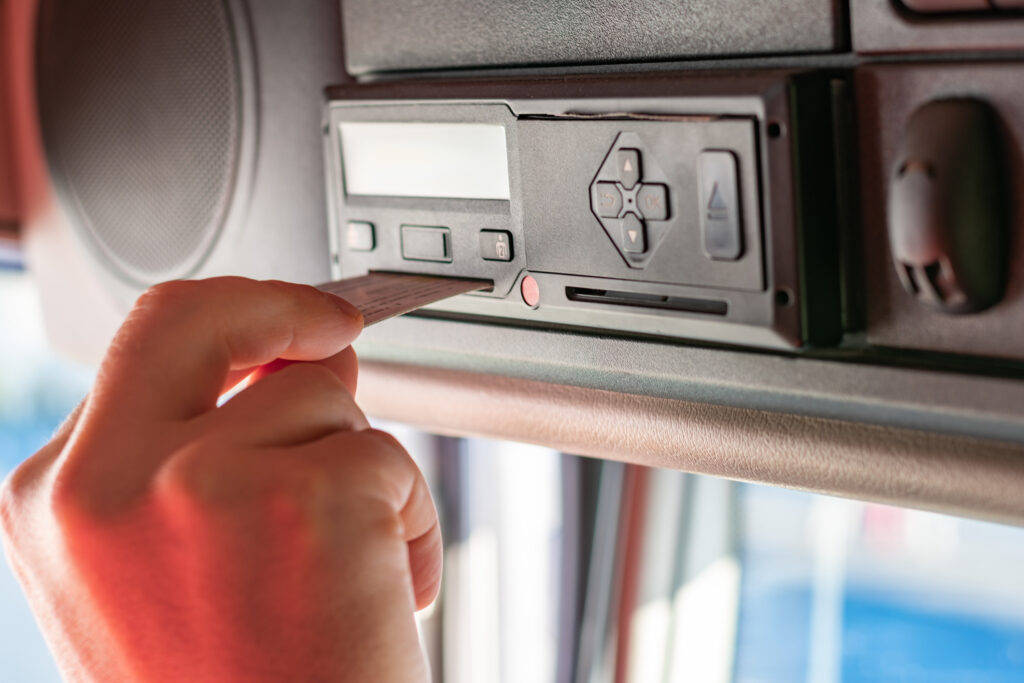 Truck driver performing driver card and menu operations on the tachograph device.