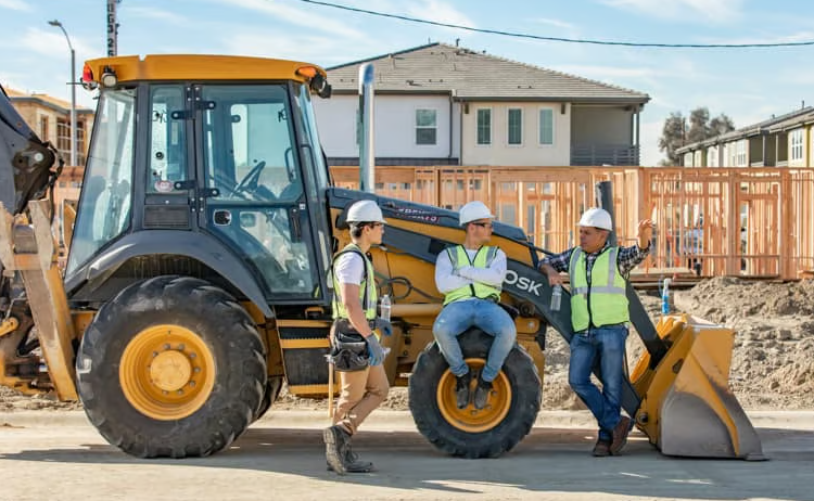 Digger plant machinery with workers beside it in hard hats