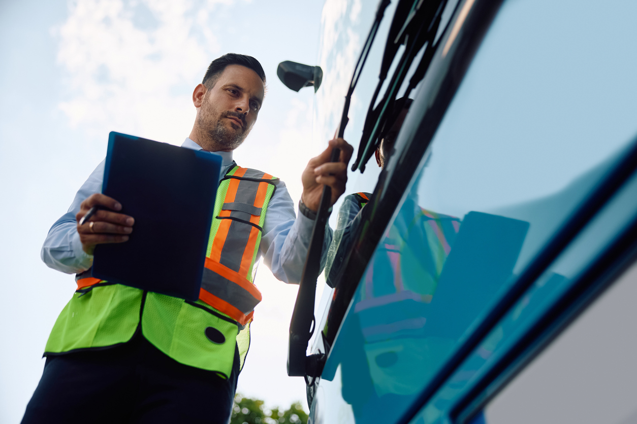 Below view of bus driver examining a vehicle before the ride.