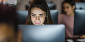 Happy student reading a lecture on desktop PC during a class at computer lab.