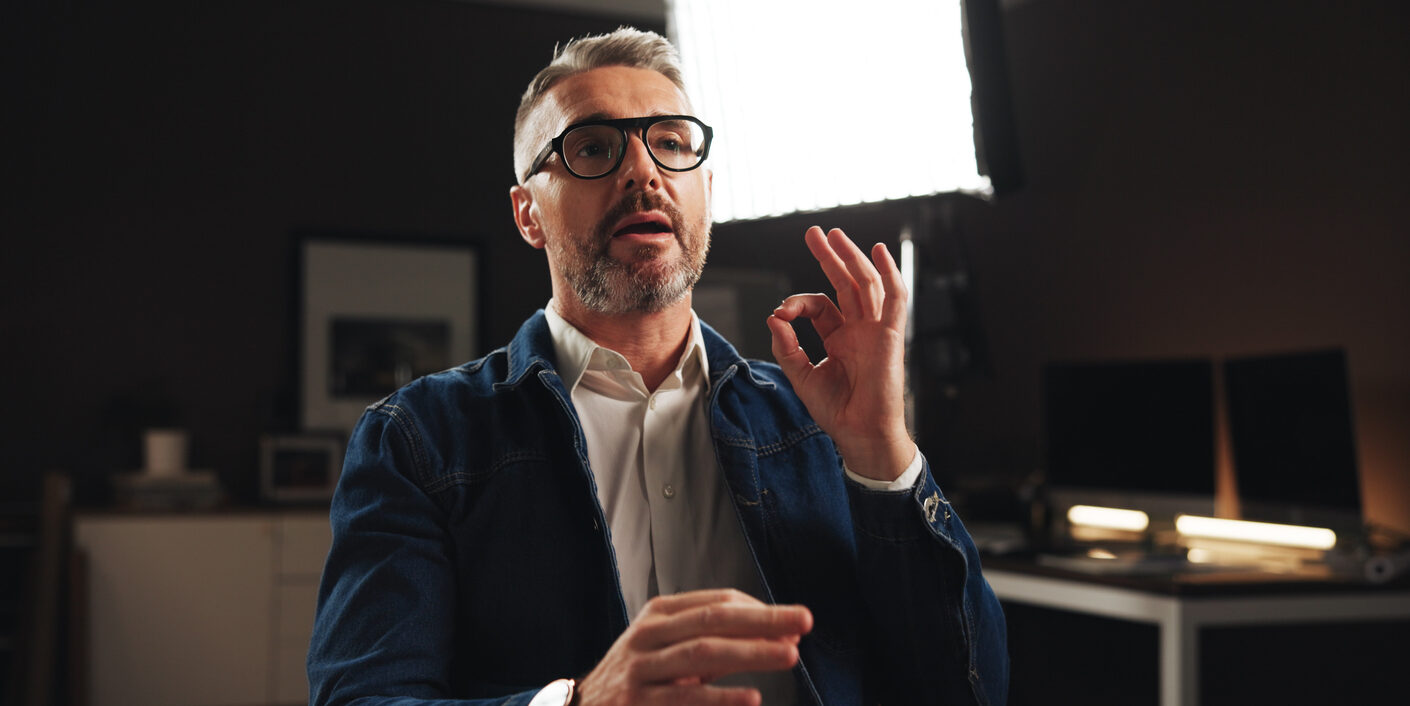 Mature man, discussion or interview with talk for online tutorial or development process. Male person, influencer or presentation with recording or documentary for helpful tips, night lesson or guide