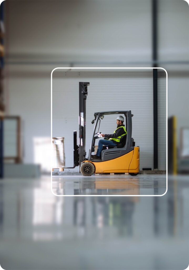 Side view of forklift in warehouse with male driver. Warehouse worker preparing products for shipmennt, delivery, checking stock in the warehouse.