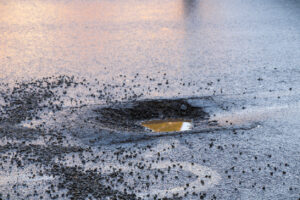 Water filled pothole with loose stone chippings