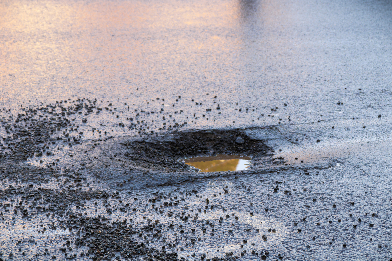 Water filled pothole with loose stone chippings
