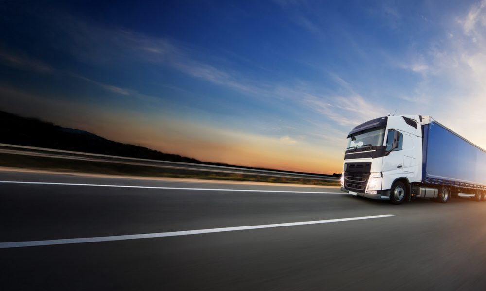 European truck driving on the asphalt road in rural landscape at sunset
